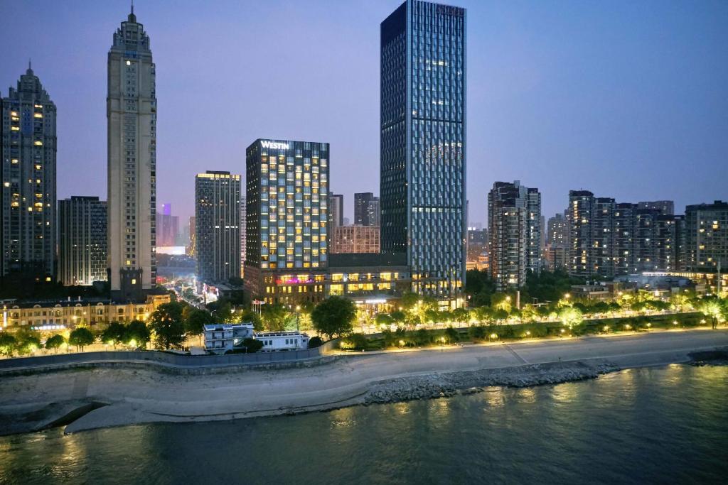 um horizonte da cidade à noite com um rio e edifícios em The Westin Wuhan Wuchang em Wuhan