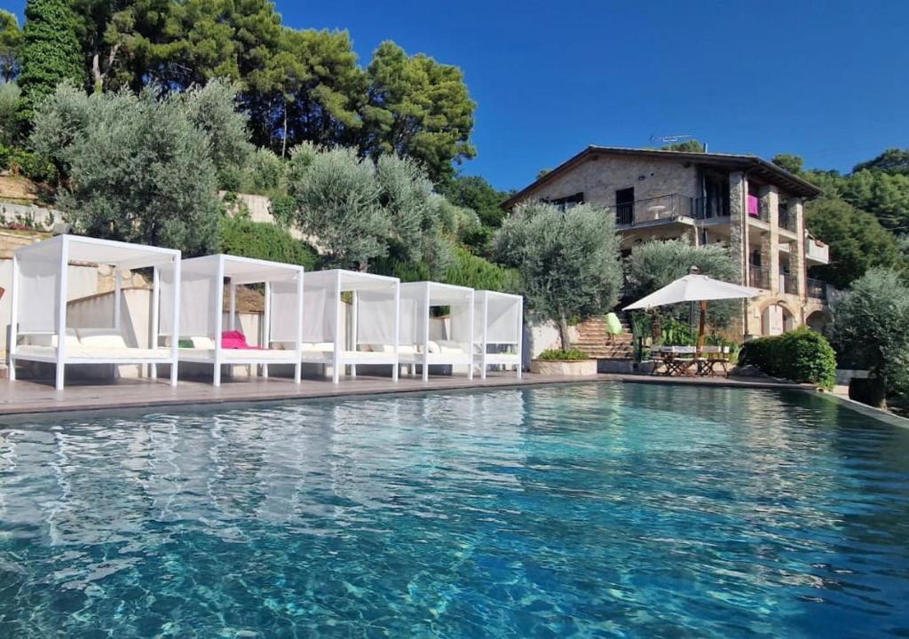 a swimming pool with white umbrellas and a house at Domus Umbra in Terni