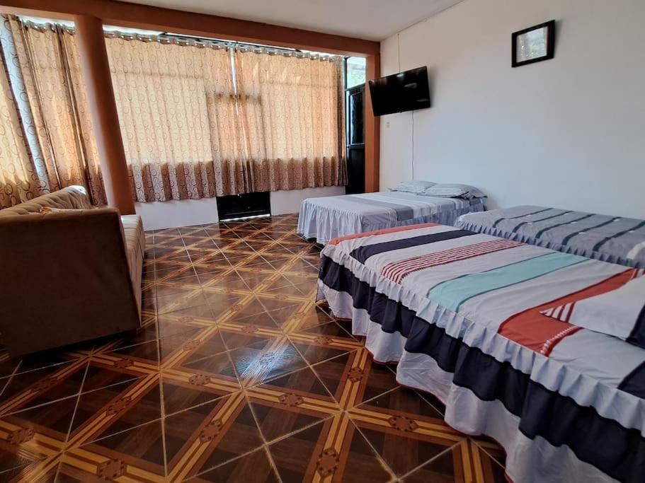 two beds in a room with a tiled floor at Departamento acogedor listo para disfrutar in Moyobamba