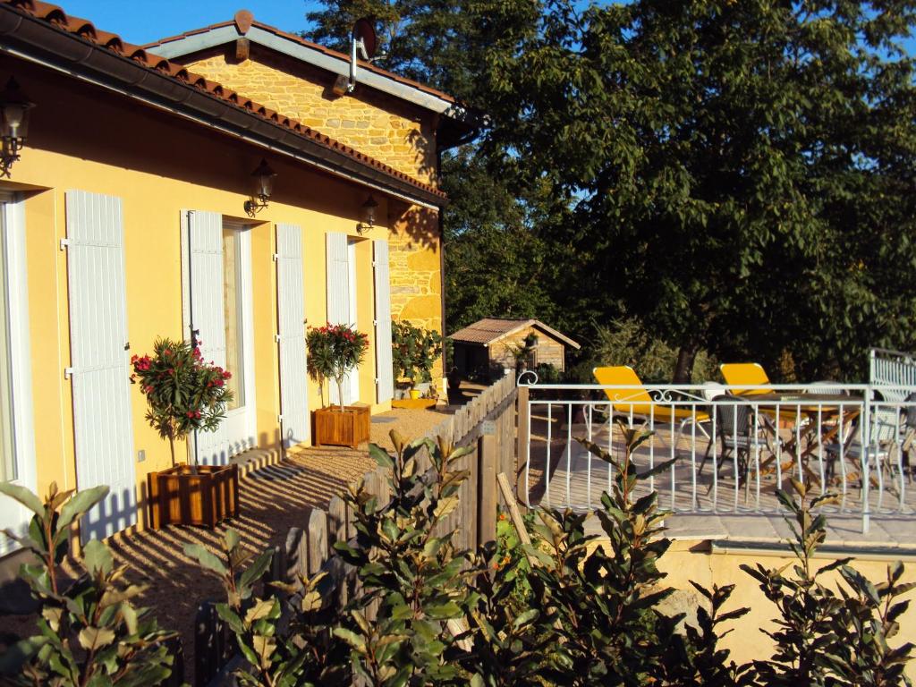 une maison jaune avec une table et des chaises sur la terrasse couverte dans l'établissement Maison d'Hotes du Vert Vallon, à Theizé
