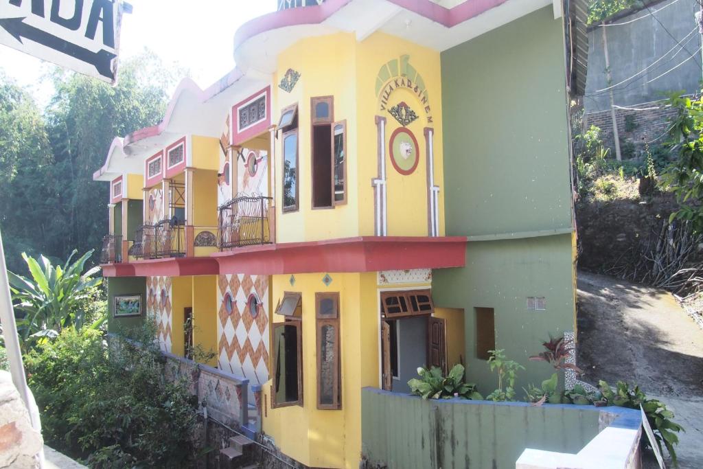 Una casa amarilla con un reloj. en OYO Life 90646 Villa Karsinem Pasuruan en Pasuruan