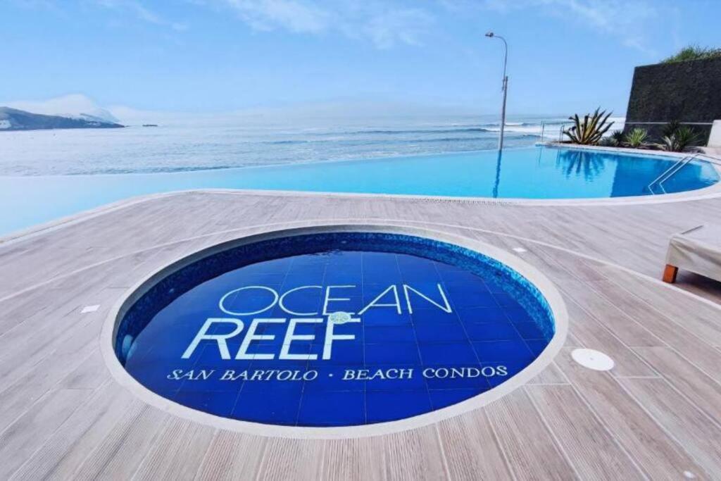 a sign that reads ocean reef next to a swimming pool at Departamento de Playa San Bartolo Ocean Reef - SOL, ARENA Y MAR in San Bartolo