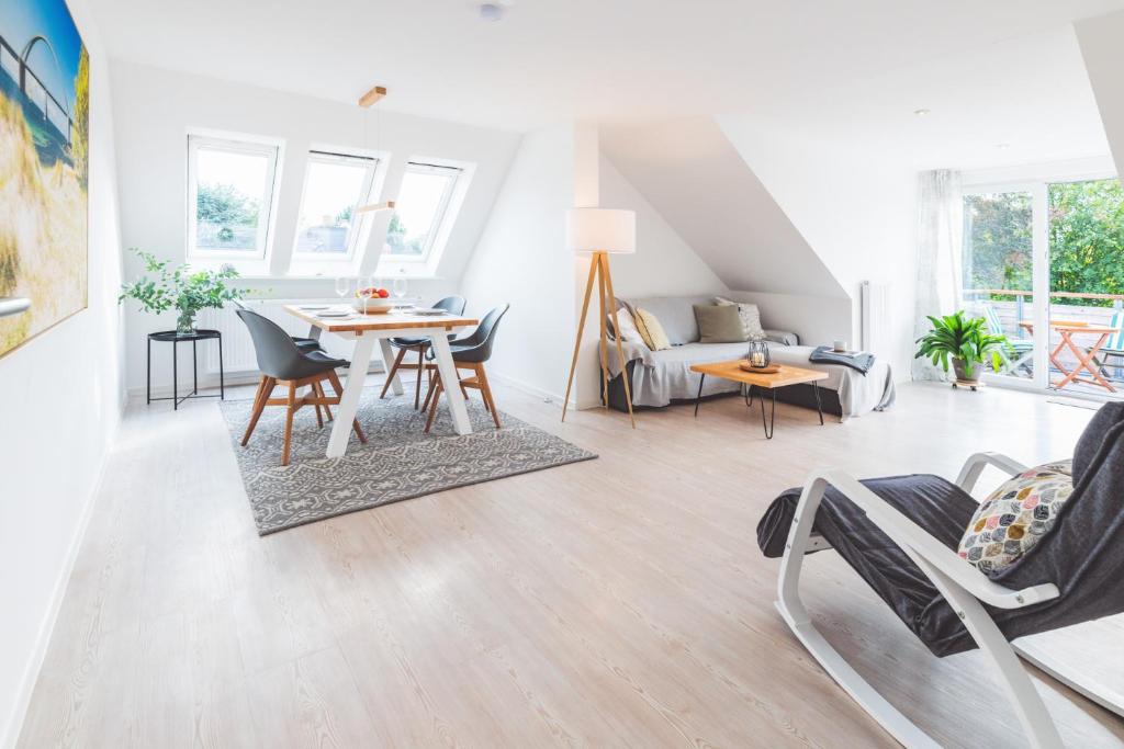 una sala de estar blanca con mesa y sillas en Casa Ueberall, en Fehmarn