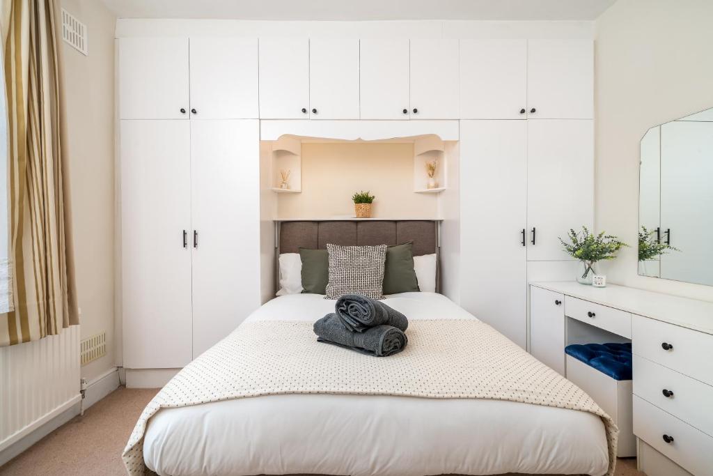 a bedroom with a bed with white cabinets at Homely and Stylish Apartment with a garden in East Finchley in London