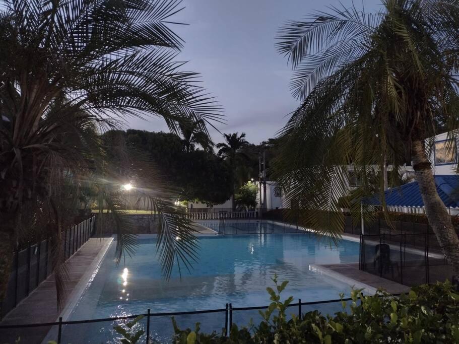 a large swimming pool with palm trees next to a fence at Buganviles 16, !Pura Vida! in Girardot