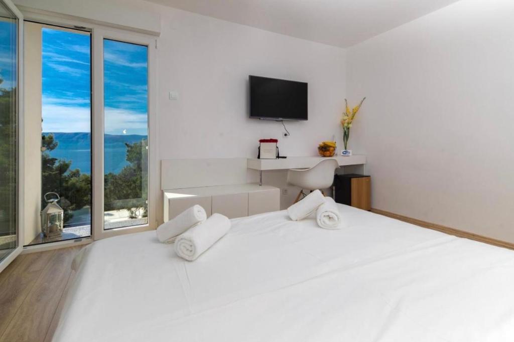 a white bedroom with a large white bed and a tv at Sea La Vie Rooms in Novi Vinodolski