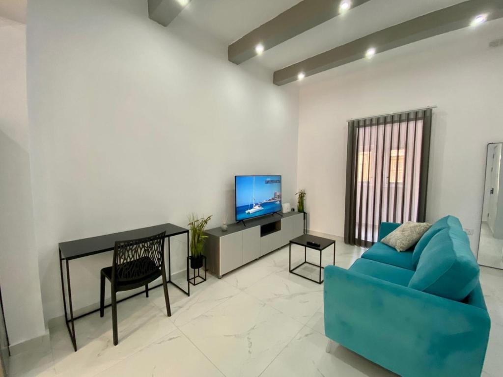 a living room with a blue couch and a television at Seaside Apartment in Gzira in Il-Gżira
