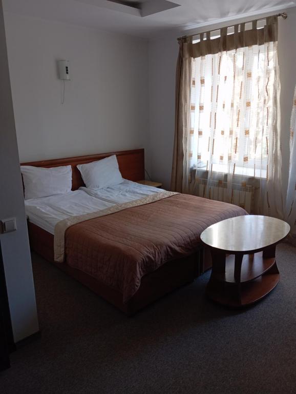 um quarto com uma cama, uma mesa e uma janela em Prestige em Lviv