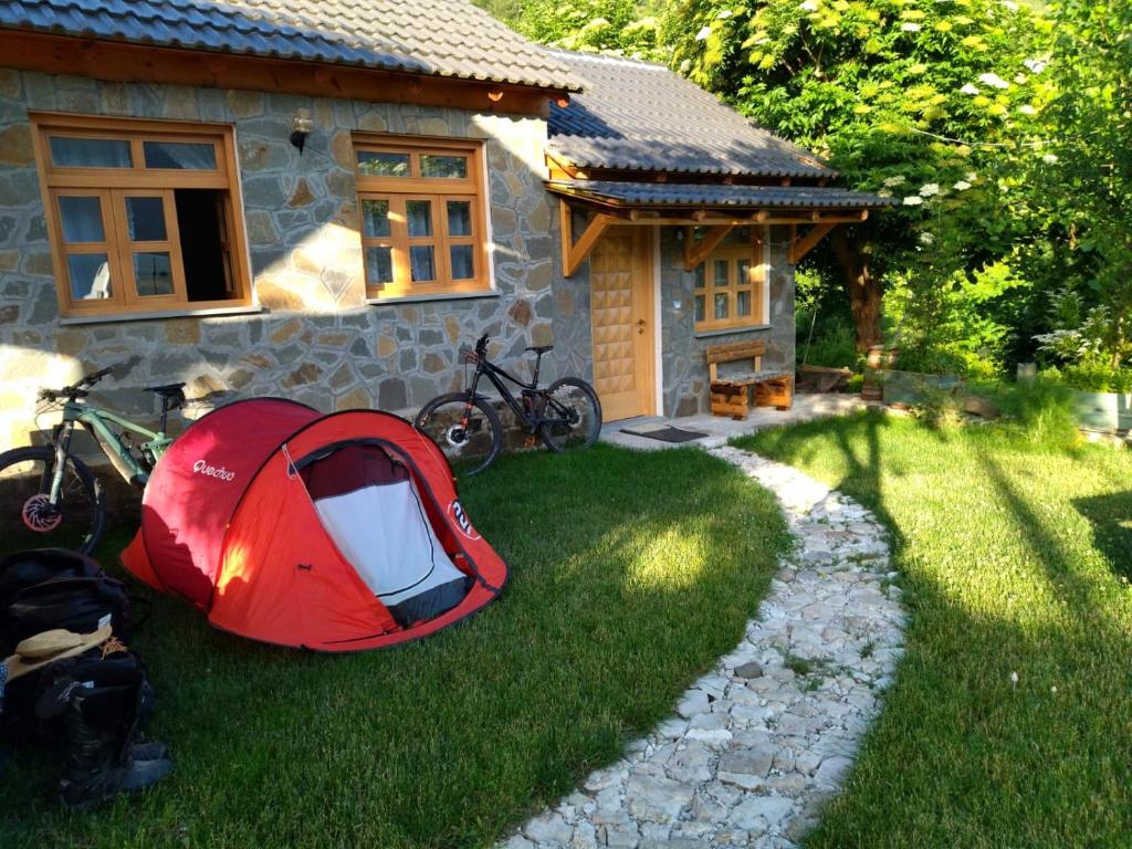 a red tent on the grass in front of a house at Bujtina Peshtan Guesthouse&Camping in Tepelenë