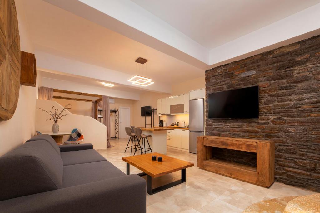 a living room with a couch and a stone wall at Andros 4 All Seasons Villas & Suites in Andros