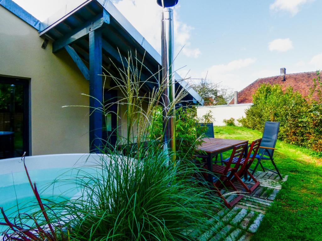 une terrasse avec une table et des chaises ainsi qu'une piscine dans l'établissement Maison chaleureuse avec son bain enchanté !, à Mesnil-Saint-Père