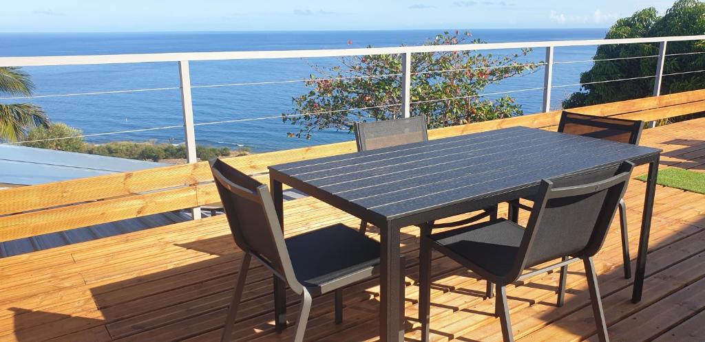 a black table and chairs on a deck with the ocean at AU PANORAMA 1 chambre in La Possession