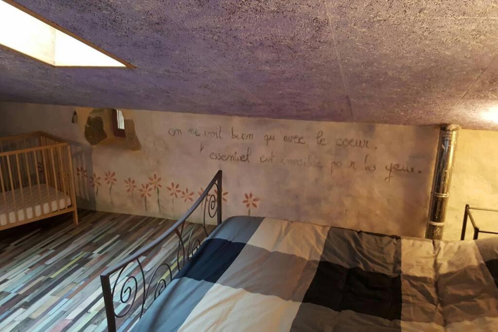 a bedroom with a bed with writing on the wall at Les papillons in Agnat