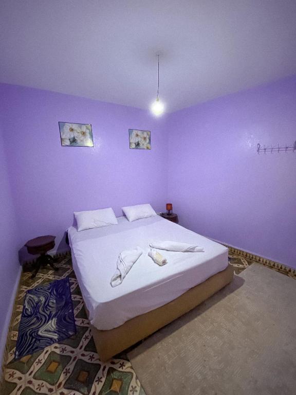 a bedroom with a large bed with purple walls at Dar Diyafa in El Ksiba