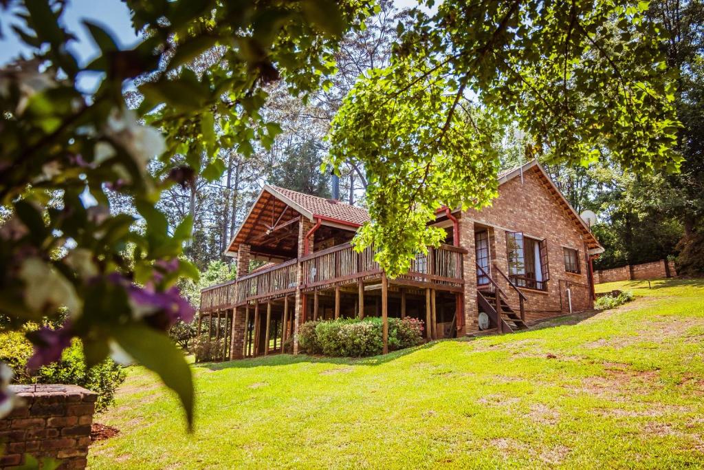 una casa en un patio de césped con árboles en Cheerio Trout Fishing & Holiday Resort, en Haenertsburg