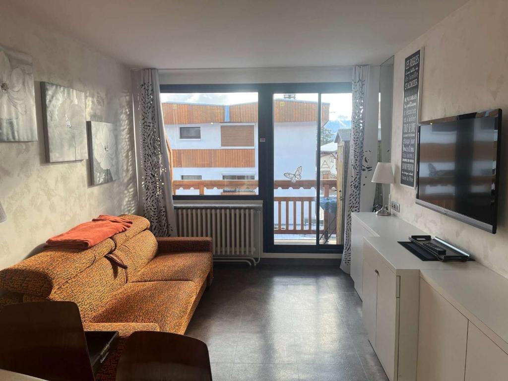 a living room with a couch and a television at Appartement Huez, 1 pièce, 4 personnes - FR-1-405-228 in LʼHuez