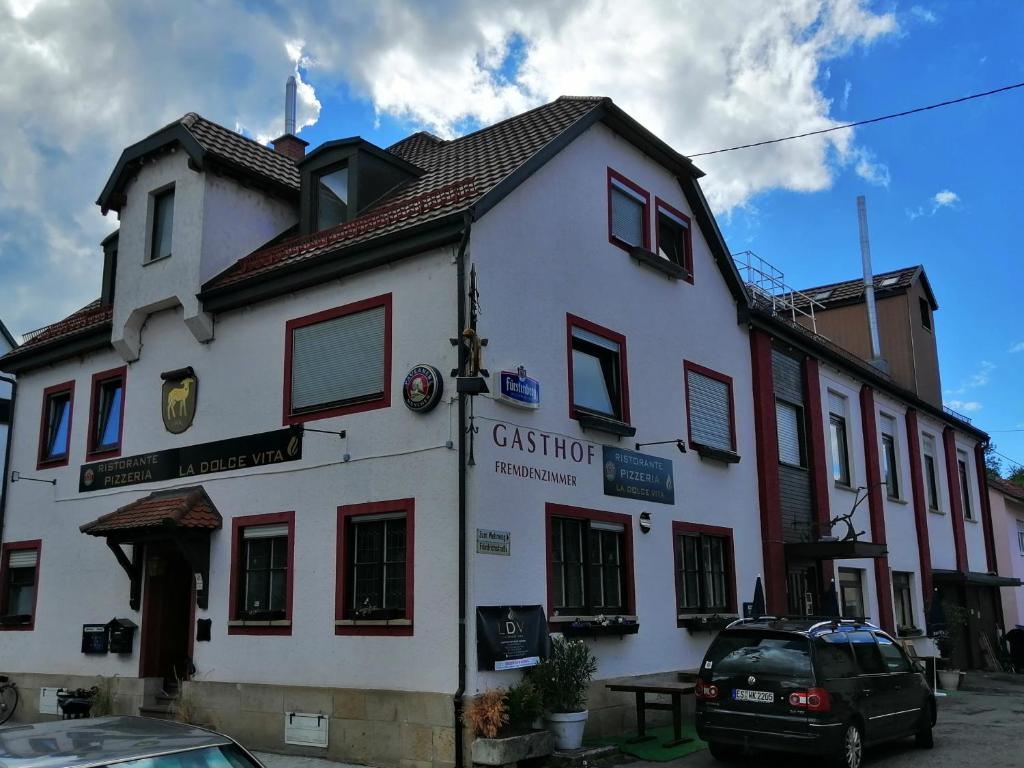 Un bâtiment blanc avec une voiture garée devant. dans l'établissement Zimmervermietung Gasthof Lamm, Zugang selbstständig über Schlüsseltresor, à Dettingen unter Teck