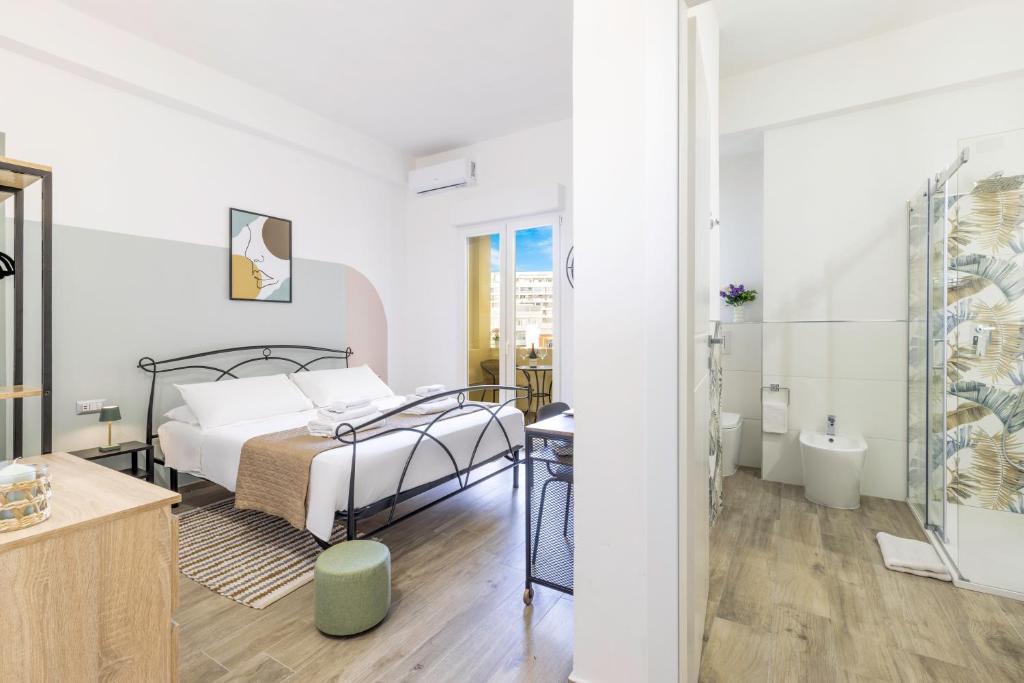 a white bedroom with a bed and a bathroom at Quarzo. Modern Rooms in Cagliari