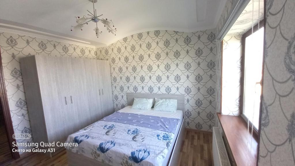 een kleine slaapkamer met een bed met een blauwe sprei bij Samarqand city in Samarkand