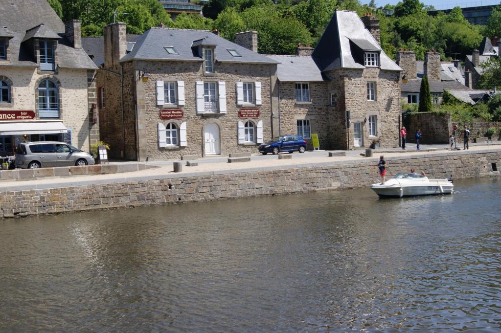 a small boat in the water in front of a building at Au Fil De L'eau - Les Remparts in Dinan