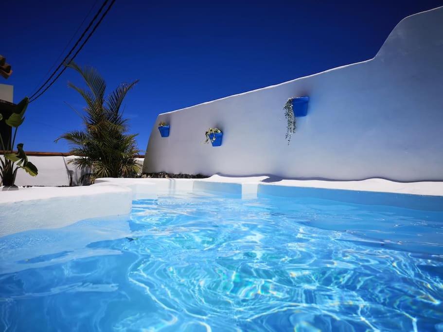 a large blue swimming pool in front of a white building at Casa rural con piscina climatizada in Icod de los Vinos