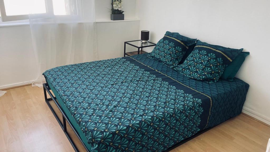 - un lit avec une couette et des oreillers verts dans l'établissement Les Essarts T3, à Bron