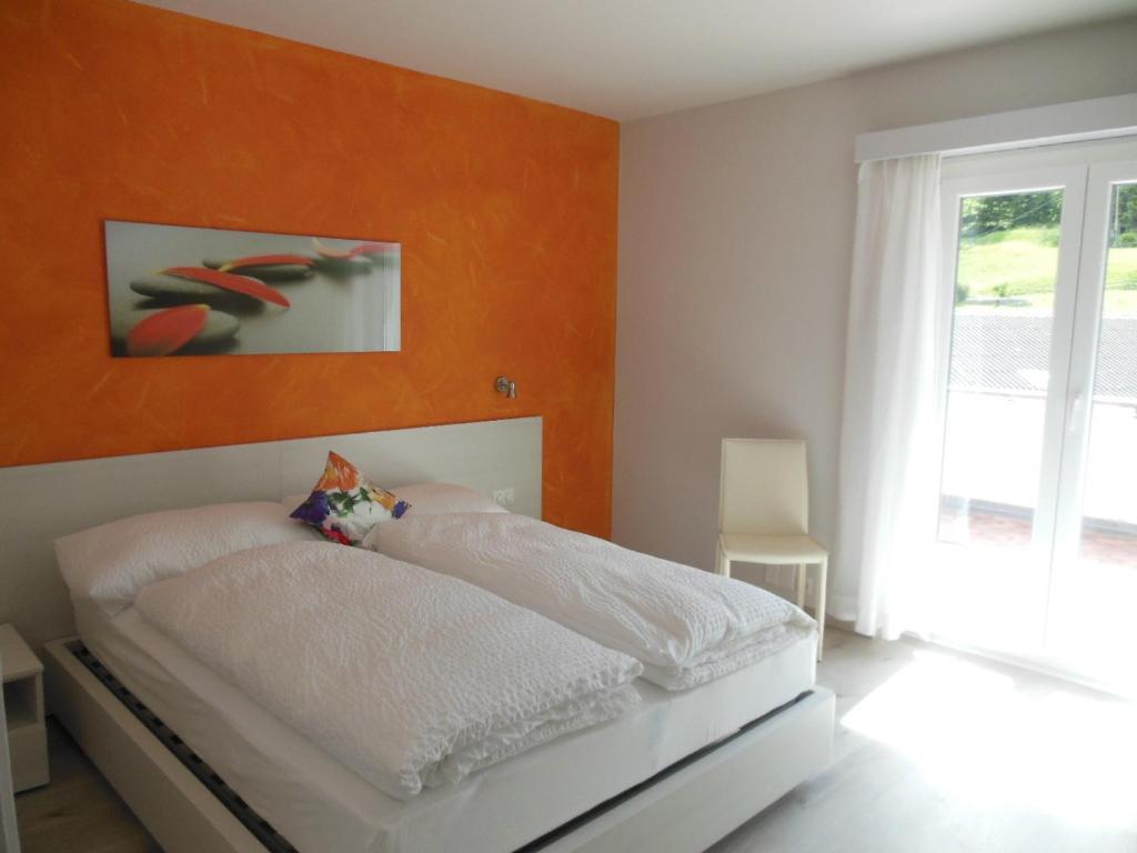 a bedroom with a white bed with an orange wall at B&B Tencia in Prato