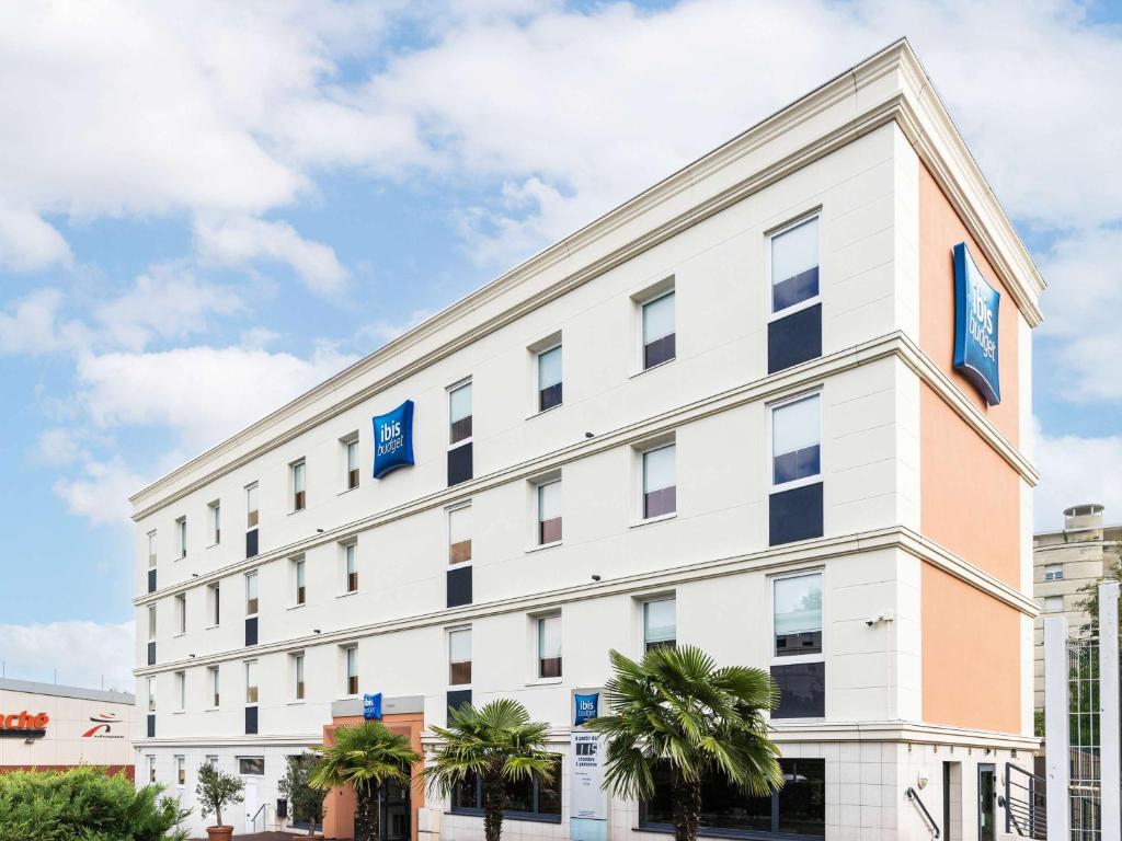 un bâtiment blanc avec des panneaux bleus dans l'établissement Hotel ibis budget Chatillon Paris Ouest, à Châtillon