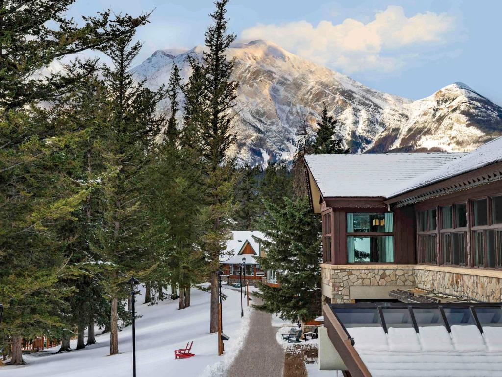 a building with a snow covered mountain in the background at Fairmont Jasper Park Lodge in Jasper
