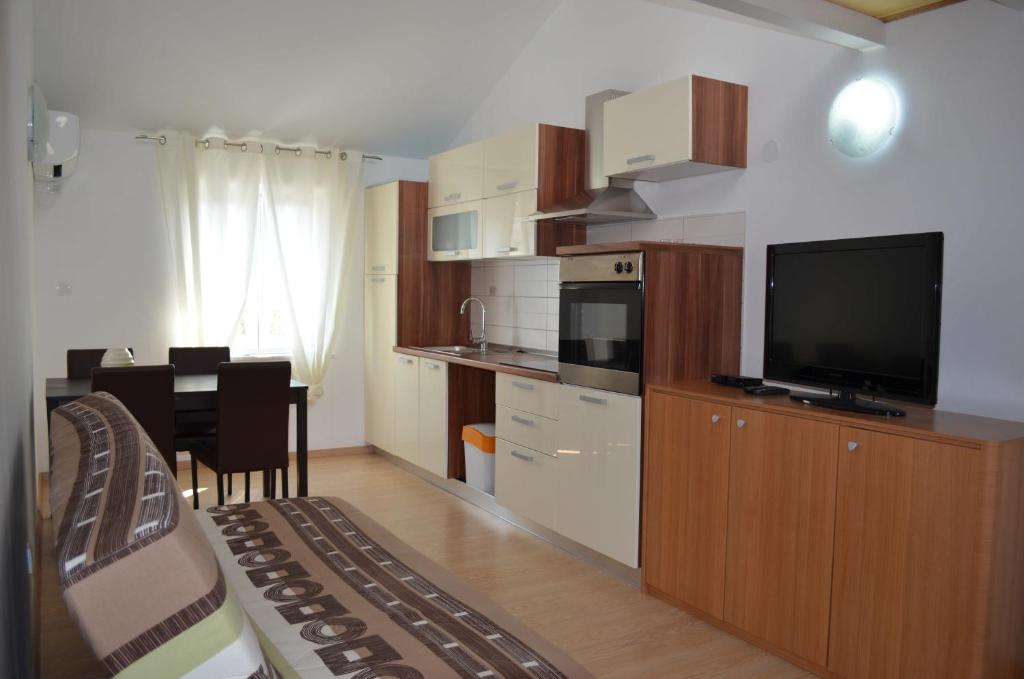 a room with a kitchen with a television and a table at Apartments Matej & Irena in Cres