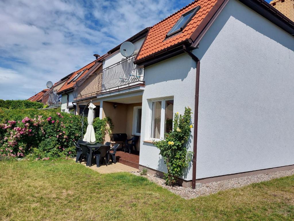 a white house with a table and a umbrella at Nella in Darłowo