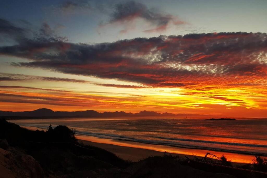 a sunset over a beach with the ocean at C the Sea 3bedroom house with 2 queen and 2 single beds max 6sleep 2bathroom walk distance to beach in Glentana Outeniqua Strand with free Wi-Fi and sea view in Outeniqua Strand