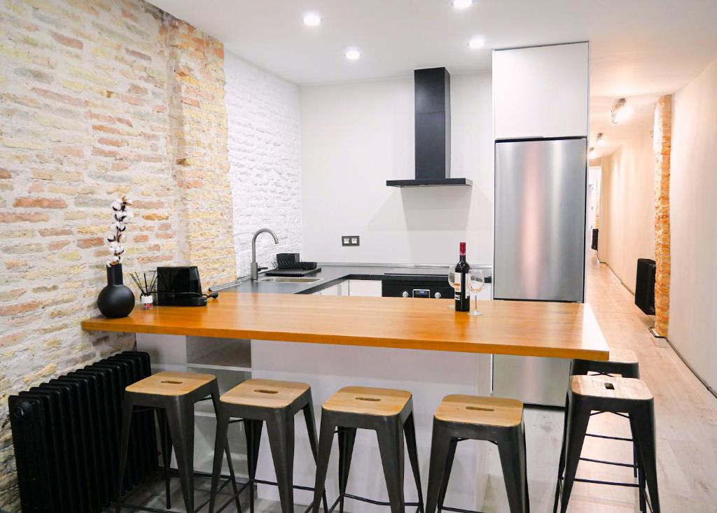 eine Küche mit einer Holztheke und Stühlen in der Unterkunft Espacioso apartamento en el centro de Pamplona in Pamplona