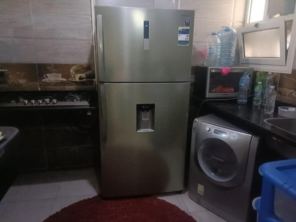 een roestvrijstalen koelkast in een keuken met een wasmachine bij سيدى بشر in Alexandrië