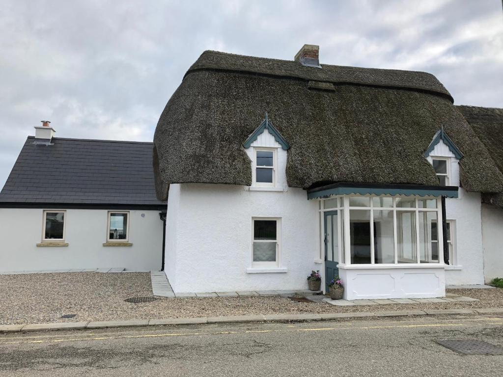 a white house with a thatched roof at Bluebell Cottage in Kilmore Quay