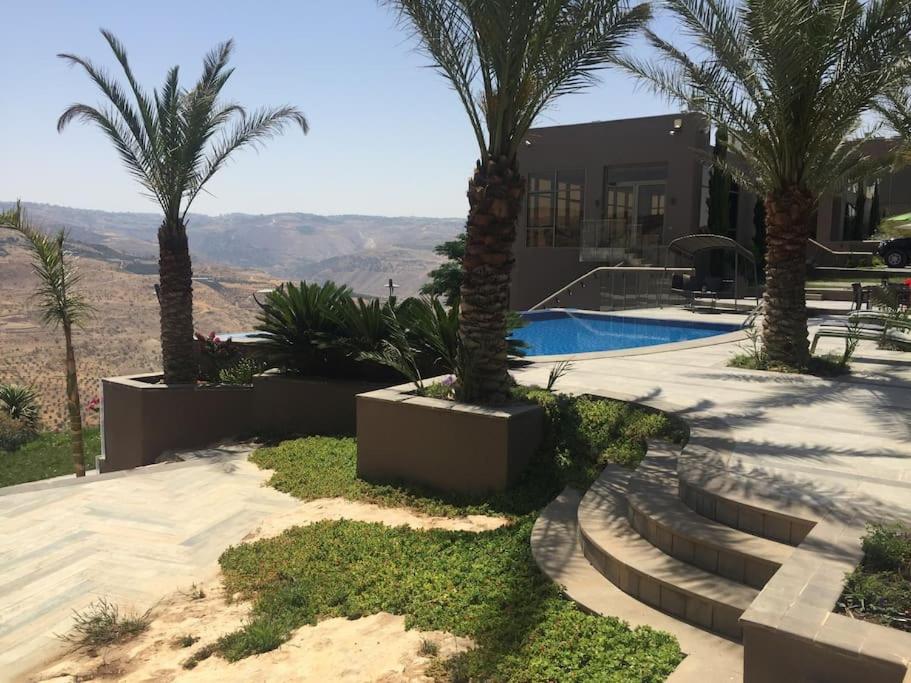 a house with palm trees and a swimming pool at Mountain Pool Suites in Amman