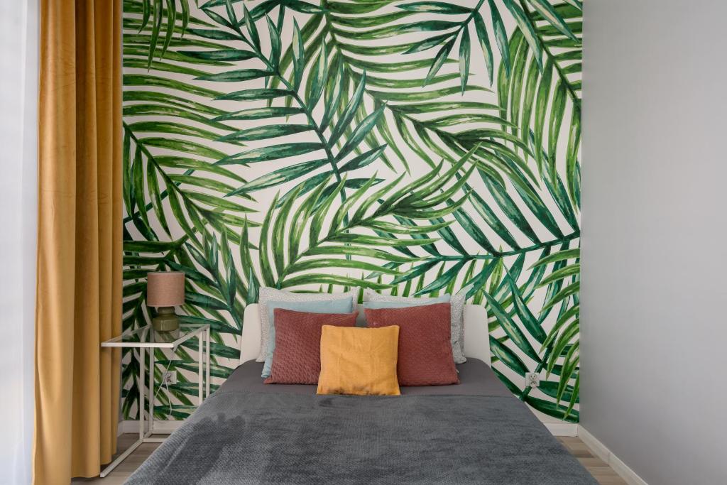 une chambre avec un lit avec un mur de feuilles vertes dans l'établissement A.S. HOME Kosciuszki, à Wrocław