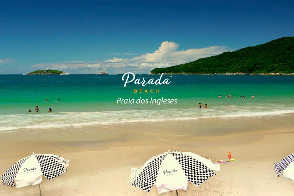 uma praia com guarda-sóis e pessoas na água em Parada Beach Beira-Mar e Aptos 70m do Mar em Florianópolis