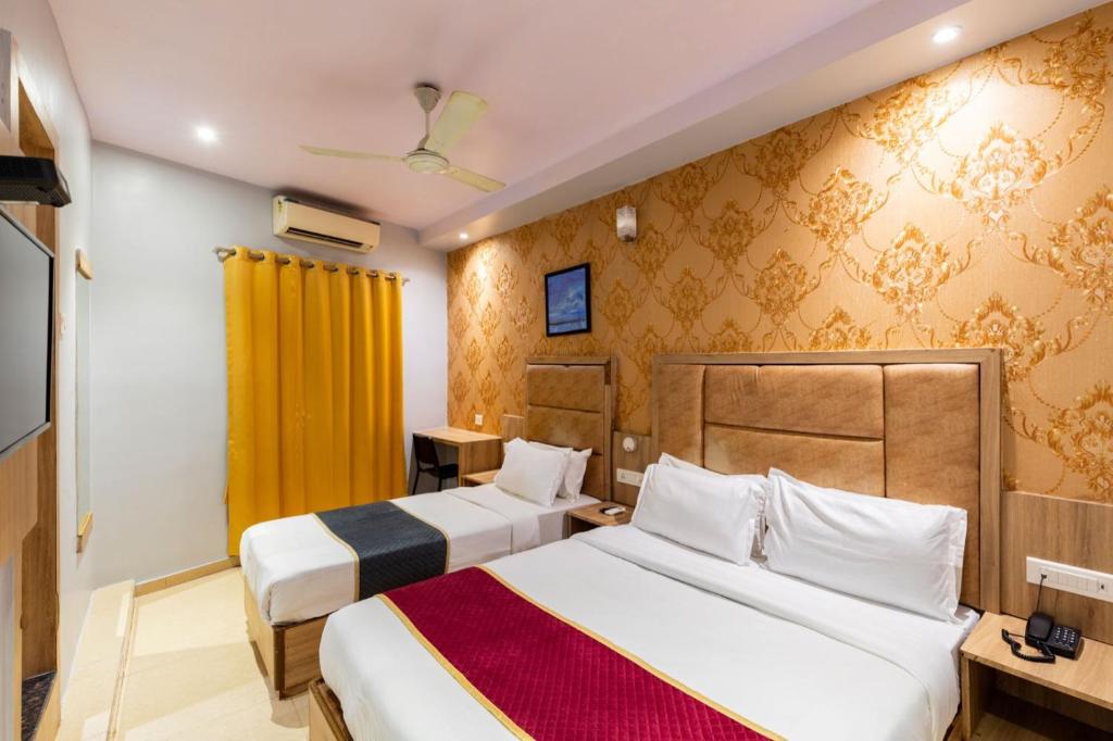 a hotel room with two beds and a yellow curtain at Lotus Grand Mumbai Near International Airport in Mumbai