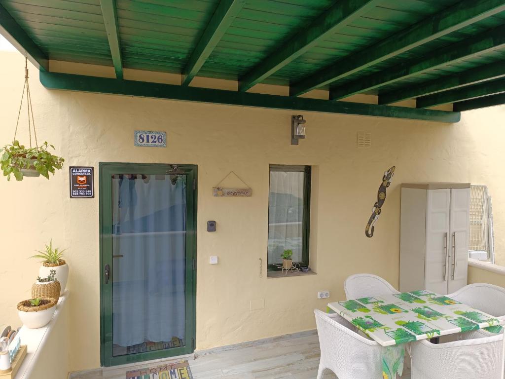 eine Terrasse mit einem Tisch, Stühlen und einer grünen Tür in der Unterkunft El Caseton in Costa Calma