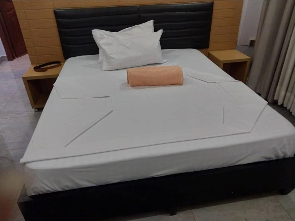 a bed with a black headboard and white sheets at KANOMBE AIRPORT BED& BREAKFAST in Kigali