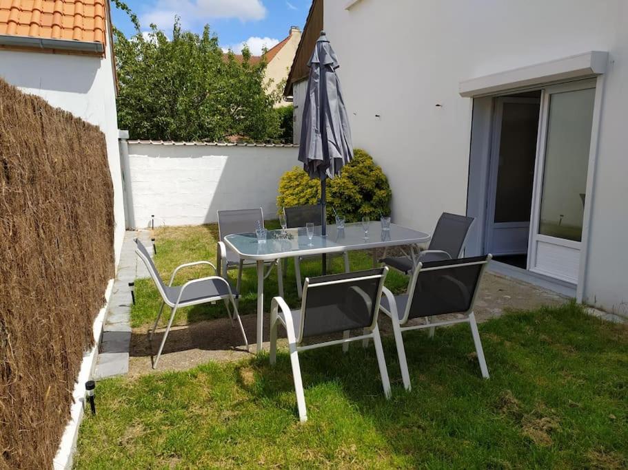 a table and chairs with an umbrella in a yard at T3 - Appartement jardin Wissant 6 personnes in Wissant