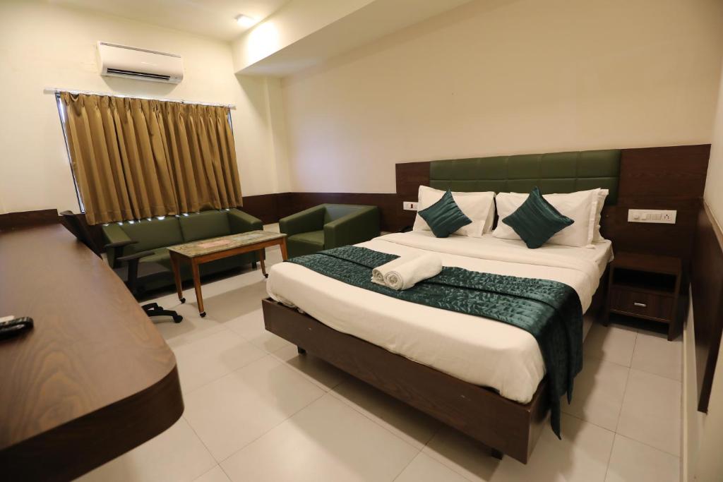 a hotel room with a large bed and a chair at Greenotel Rooms Hazira, Surat in Surat