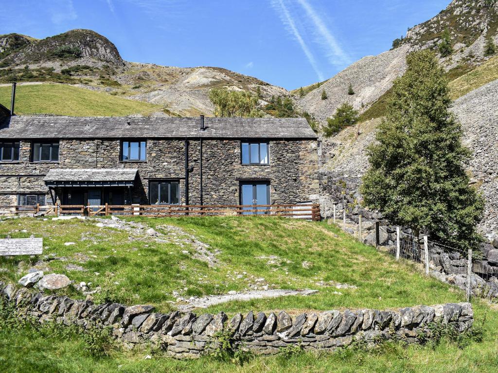 a stone house on top of a grassy hill at Striding Edge Cottage in Glenridding