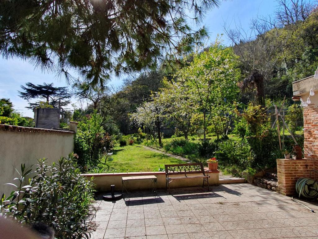 eine Terrasse mit einer Bank im Garten in der Unterkunft Chambre d'hôtes PMR Hildegarde in Moissac