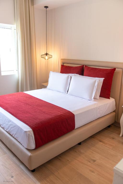 a bedroom with a large bed with red and white pillows at Santa Cruz Boutique Hotel in Mindelo