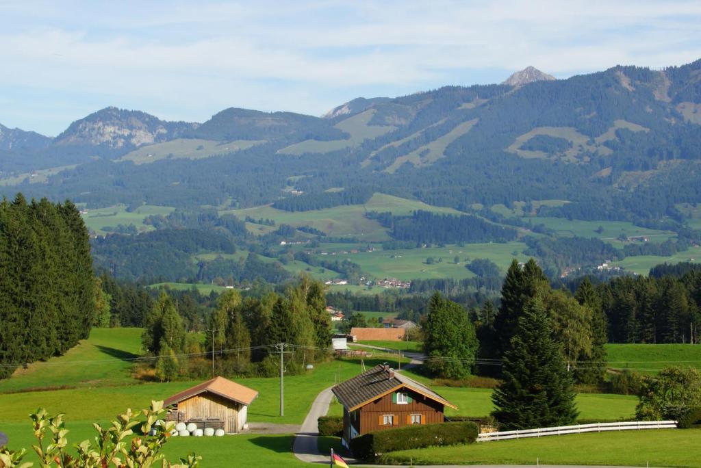 ein grünes Feld mit Häusern und Bergen im Hintergrund in der Unterkunft Ferienwohnung Karin in Bolsterlang