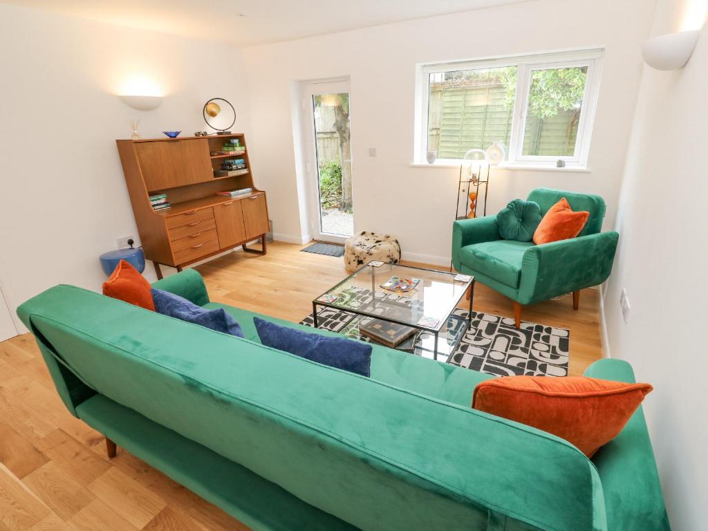 a living room with a green couch and two chairs at James' Place in Falmouth