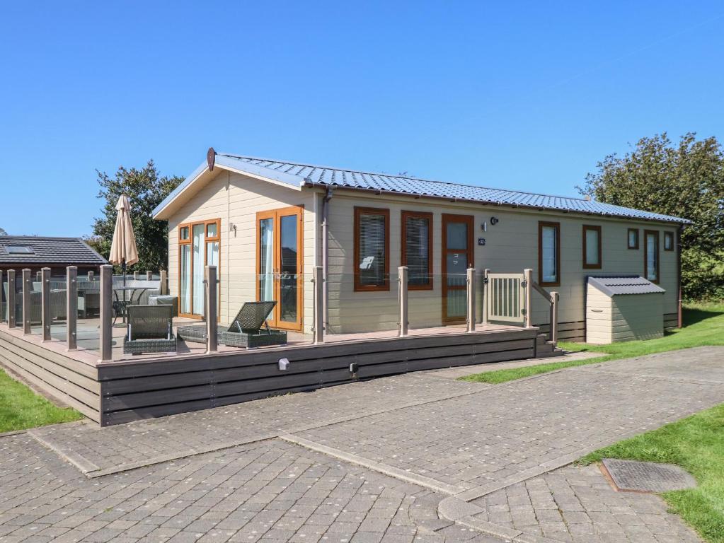 a small house with a large wooden deck at 32 Sanctuary Lodge in Pwllheli
