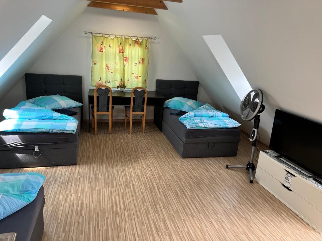 um quarto no sótão com 2 camas e uma mesa em Guesthouse David em Augsburg